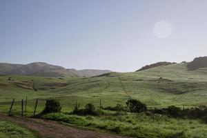 Rolling green hills countryside fence photo