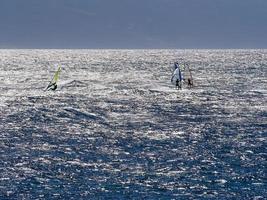 Blue water three windsurfers briiliant sun photo