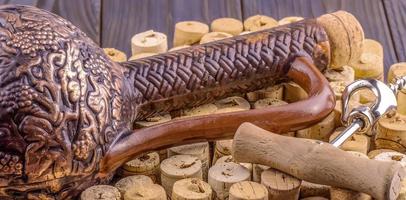 Clay bottle, metal corkscrew and cork on a wooden table photo