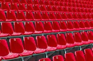 Folded red plastic chairs on a temporary tribune. Selective focus photo