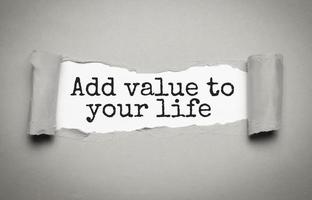 ADD VALUE TO YOUR LIFE - text on torn paper on white desk in sunlight. photo