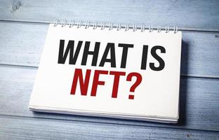 Paper with WHAT IS NFT on wooden desk photo