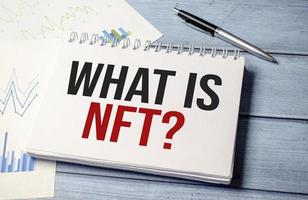 Paper with WHAT IS NFT on wooden desk photo