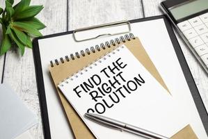 Find The Right Solution text on white notebook and pen on wooden background photo