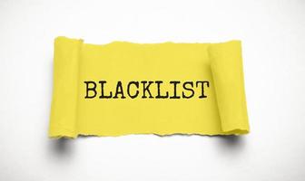 Word Blacklist on white background through hole in yellow paper, top view photo