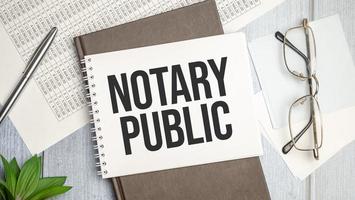 Notary public on notepad and various business papers on brown background photo