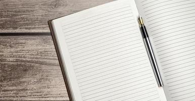 Notepad, pen and glasses on wooden desk photo