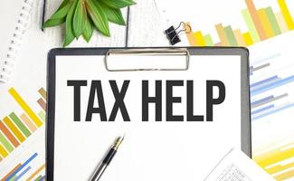 tax help word on file folder with pen, charts and notebook photo