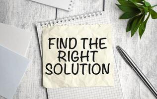 Find The Right Solution text on white notebook and pen on wooden background photo