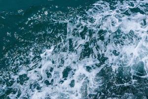 Beautiful sea waves with foam of blue and turquoise color. Abstract blue sea water with white wave. Blue and white waves of the ship road on the water sea ocean. photo