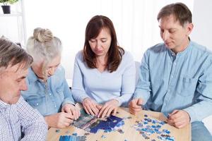 Family gathers puzzle together at table at home photo