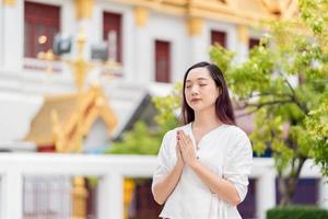 portrait young asian woman wearing traditional dress of Thailand praying at Wat Ratchanatdaram photo