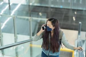 young woman talking with mobile phone and wearing face mask protective for spreading of coronavirus covid-19 pandemic, new normal concept photo