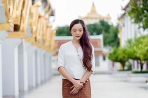 retrato de una mujer budista asiática con un vestido tradicional de tailandia en la iglesia para relajarse y meditar, santuario ratchanatdaram bangkok. foto