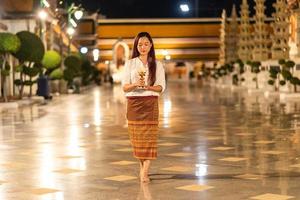 Portrait asian buddhist woman wearing traditional dress of Thailand holding candle and walking around at Wat Suthat Thepwararam photo