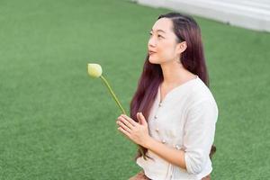 young asian woman holding lotus and praying for lucky photo