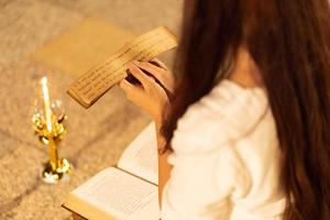 mujer asiática con vestido tradicional de tailandia leyendo sánscrito antiguo libro tripitaka del señor buddha dhamma, santuario ratchanatdaram bangkok. en la noche foto