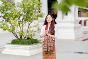 portrait Asian buddhist woman wearing traditional dress of Thailand praying at Wat Ratchanatdaram bangkok photo