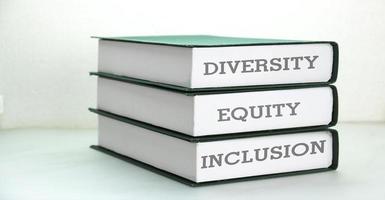 libros con palabras dei, diversidad, equidad, inclusión en mesa con fondo blanco. foto
