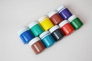 Closed jars with gouache of different colors on a light background. Creativity, drawing, paints, art, hobby. photo