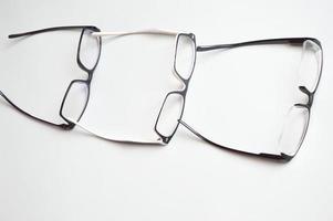 lentes ópticos, en un marco negro, acostados en fila sobre un fondo blanco. corrección de la visión, accesorios, oftalmología. foto