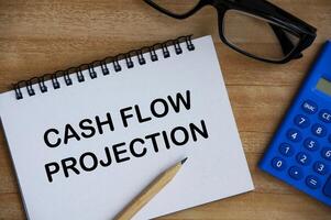 Cash flow projection text on notepad with calculator, pencil and glasses background. Business concept photo