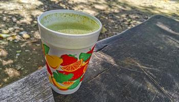 Green smoothie juice on bench in a park wooden background. photo