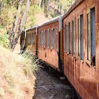 Toy Train moving on mountain slopes, beautiful view, one side mountain, one side valley moving on railway to the hill, among green natural forest. Toy train from Kalka to Shimla in India photo