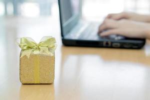 Female working on laptop and wrapping gifts photo