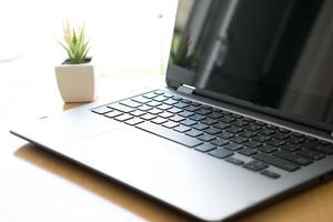 Workspace with laptop computer, office supplies flower plant at home photo