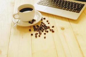 laptop, cup of fresh coffee and coffee beans photo