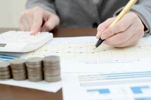 Close up woman using calculator on paper graph data photo