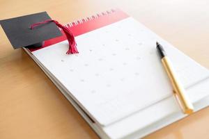 bolígrafo en el calendario y gorra de graduación foto