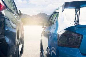 Rear side of two car on the asphalt road with bright light. Parking on the road or prepare for race. with blurred background of forest and mountain under the blue sky. photo