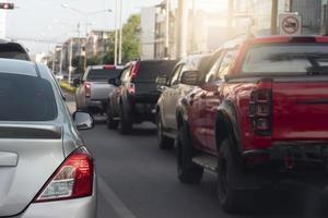 parte trasera del coche plateado en la carretera asfaltada en dirección a la meta del viaje. viajando por trabajo durante la hora pico. ambiente de desenfoque de otros autos en la ciudad. foto