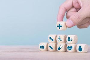 Hand chooses a emoticon icons healthcare medical symbol on wooden block , Healthcare and medical Insurance concept photo