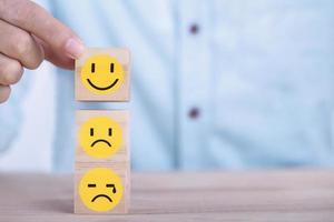 Businessman chooses a smile emoticon icons face happy symbol on wooden block , Services and Customer satisfaction survey concept photo