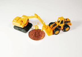 figura de excavadora y excavadora de pie frente a bitcoin. concepto de minería bitcoin. foto