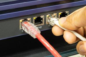Hand of a man holding The network cables to connect the port of a switch to connect internet network, concept Communication technology photo