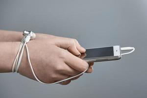 Female hands and smartphone. Addiction to internet and social networks. Hands tied with wire. photo