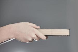 Hands holding closed book on a gray background. photo