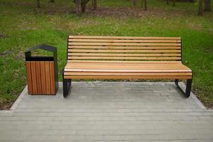 Wooden bench and trash can in the park. photo