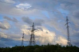 líneas eléctricas de alto voltaje con torres de alta tensión contra el fondo del cielo nublado de la noche. foto
