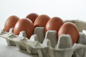 Eggs close up in protective container on white background. Foreground and background in blur. photo