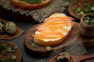 Butter and trout sandwich on a wooden Board. Diet Breakfast sandwich with red fish, quail eggs and greens. photo