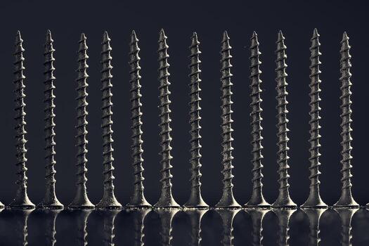 Neatly arranged screws in a row. Self-tapping screws with a reflection on a black background. photo
