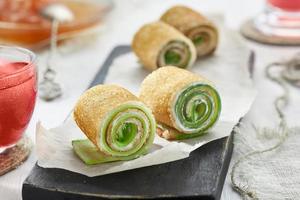 Homemade pancakes rolls with soft cheese and cucumber.
