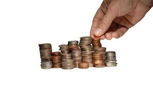 a pile of coins on a table and hand adding coins to the pile isolated on a white background photo