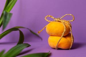 Fresh peach on a purple background with green leaves on a side photo