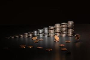 stacks of coins on a black background with falling coins photo